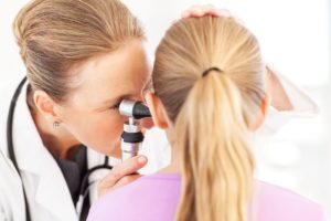 Procedures an otolaryngologist perform include myringotomies. In this image, a doctor is using a scope to look into a girl's ear.